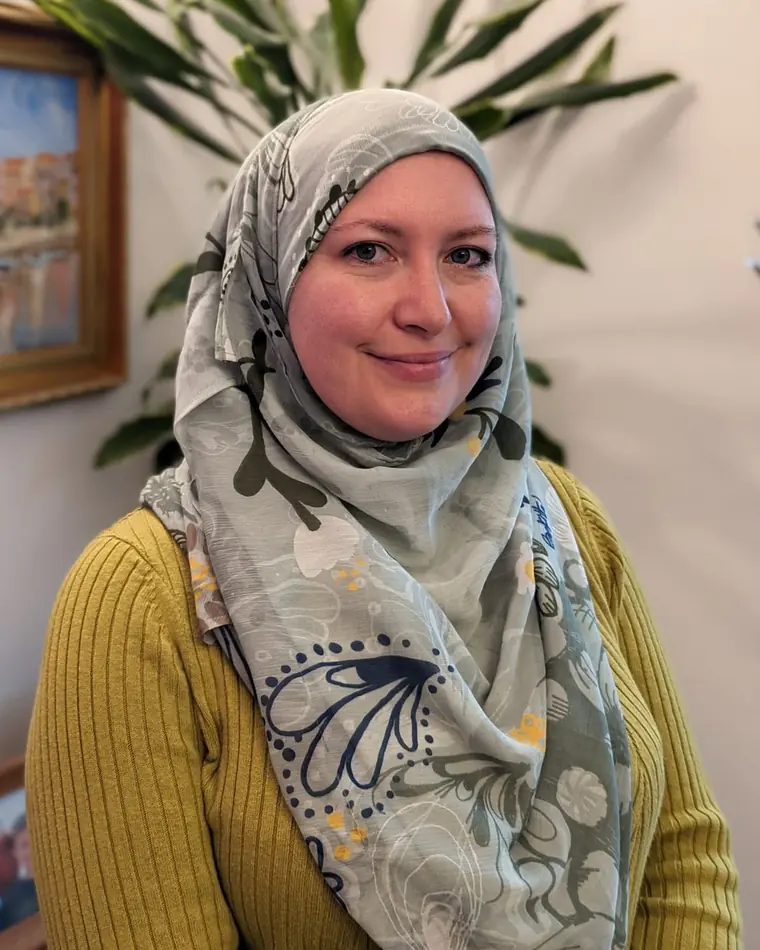Natalie Mohammed, author, photographed in a green scarf and mustard cardigan.